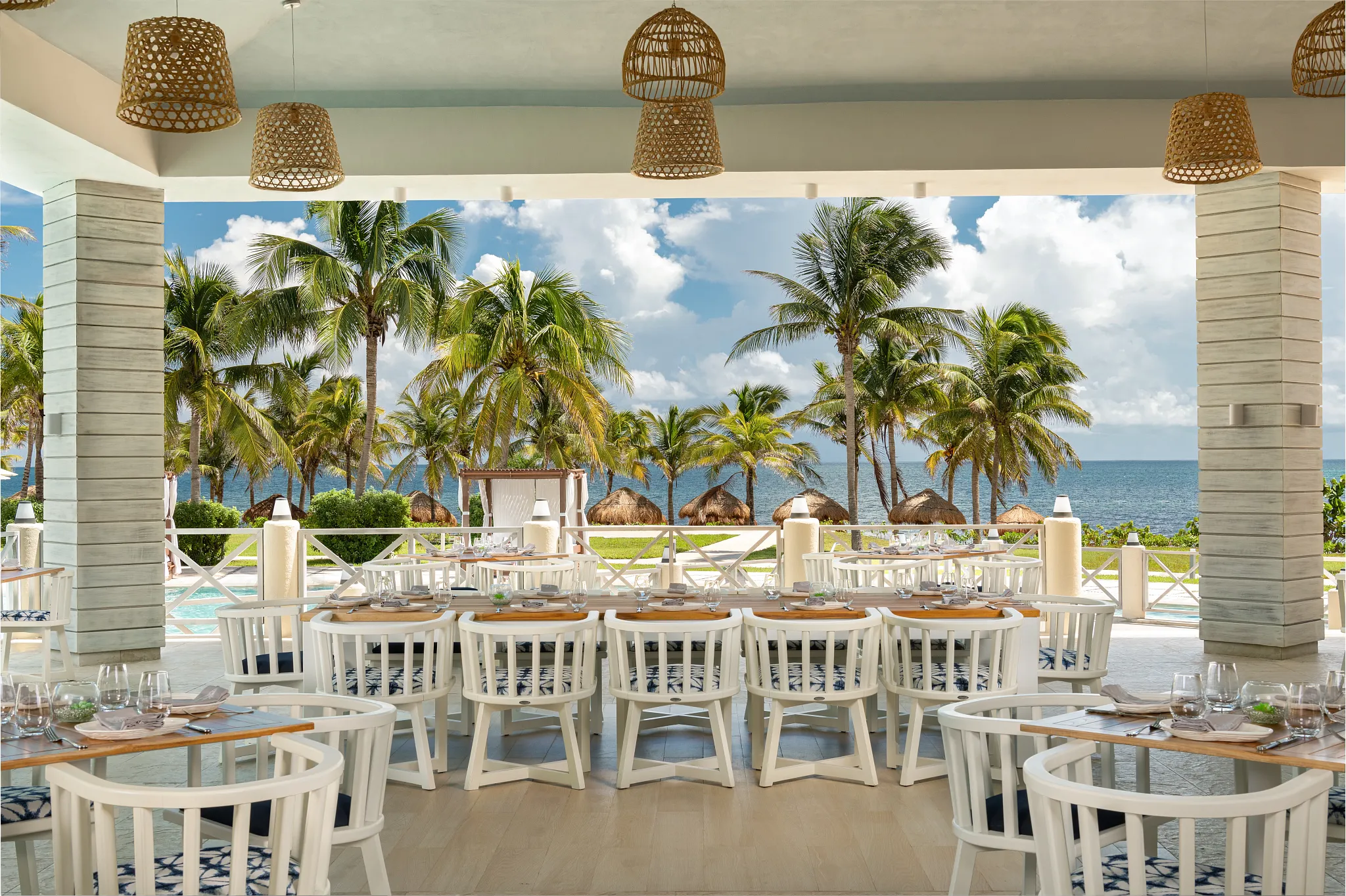 Balik seafood restaurant at Dreams Puerto Morelos Resort & Spa featuring open-air dining, ocean views, palm trees, and coastal-inspired seating.