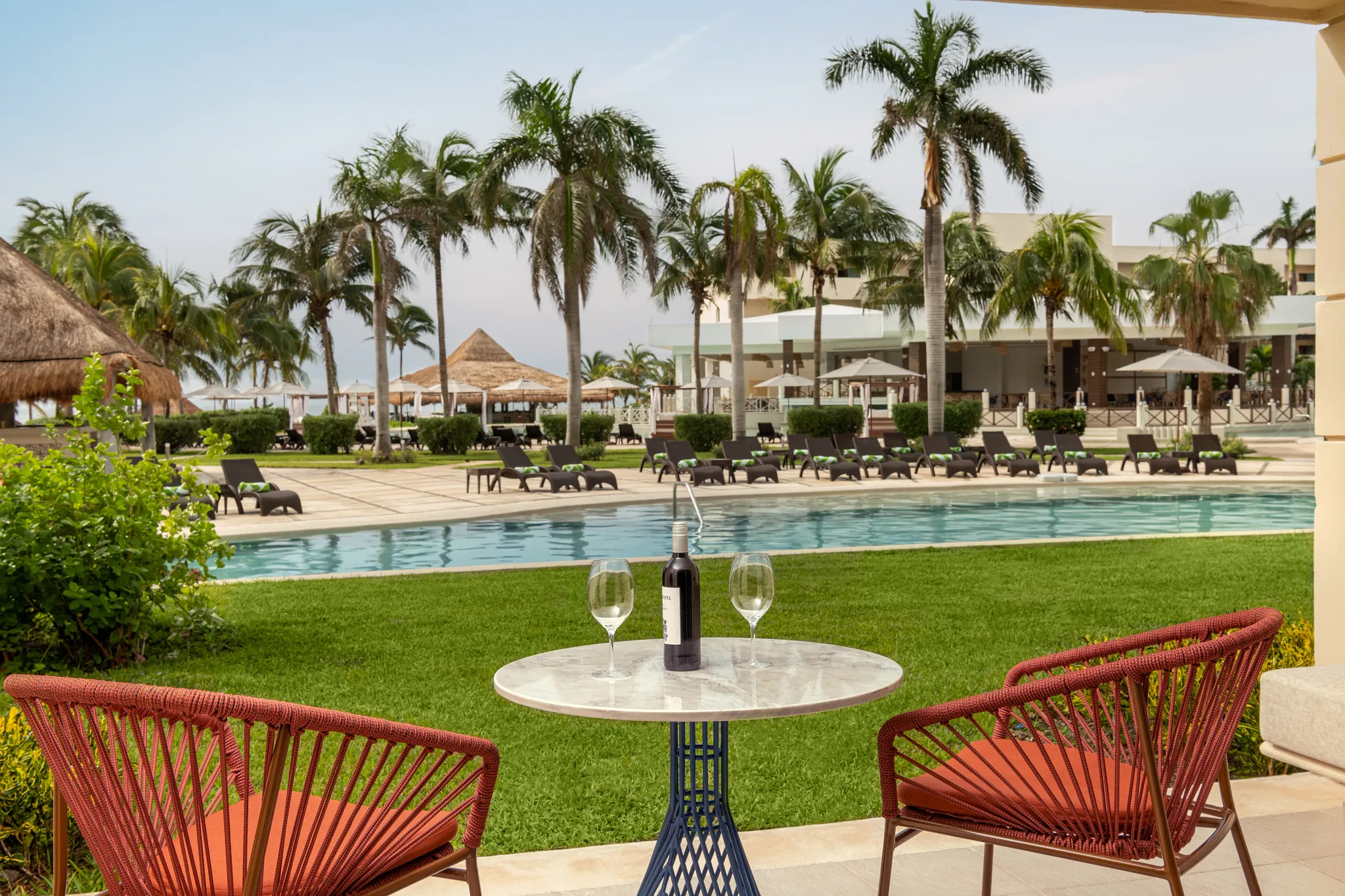 Junior Suite Pool View King balcony with seating overlooking pool and palm trees at Dreams Puerto Morelos Resort.