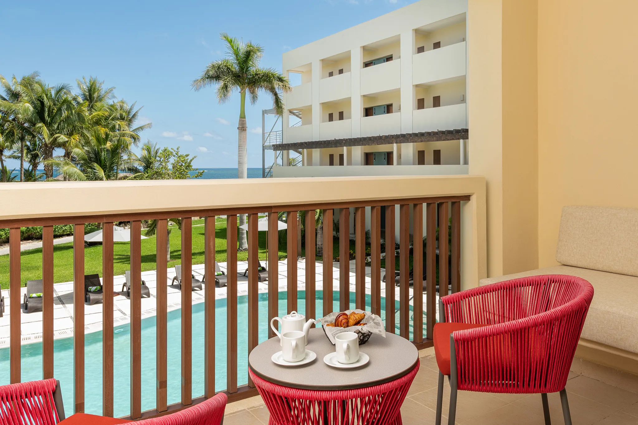 Junior Suite Tropical View balcony with seating overlooking pool and tropical gardens at Dreams Puerto Morelos Resort.