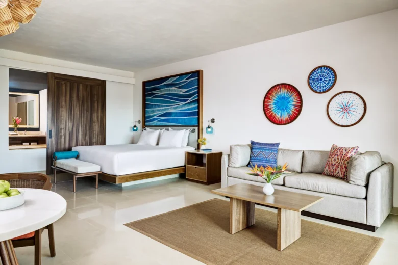 Junior Suite Tropical View King bedroom with sofa and modern decor at Dreams Puerto Morelos Resort.