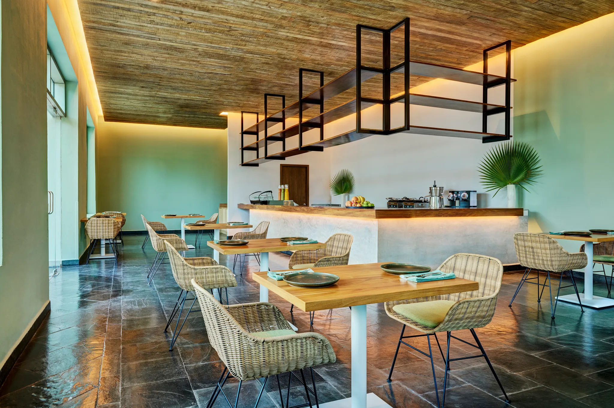 Roots coffee and snack bar at Dreams Puerto Morelos Resort & Spa featuring a modern café interior, wicker seating, and light wood tables.