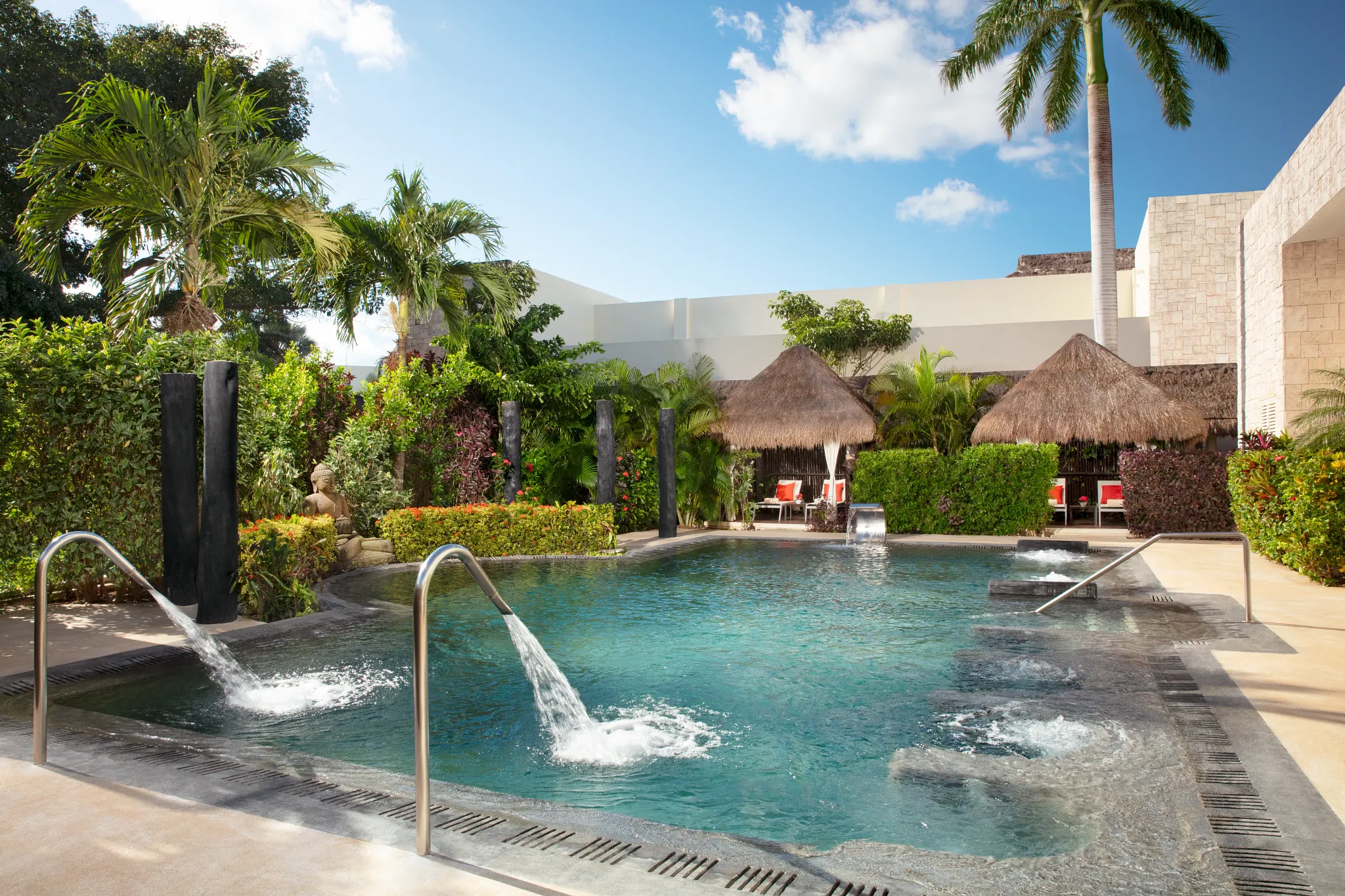 Outdoor hydrotherapy pool with jets and tropical landscaping at resort spa.